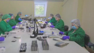 Fabrika işçileri hap taşıyor. Maskeli işçiler. Bir ilaç fabrikasında iş akışı