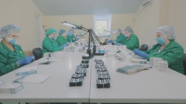 Kadınlar bir pakette hap paketler. Maske takan fabrika işçileri. bir salgın sırasında çalışmak