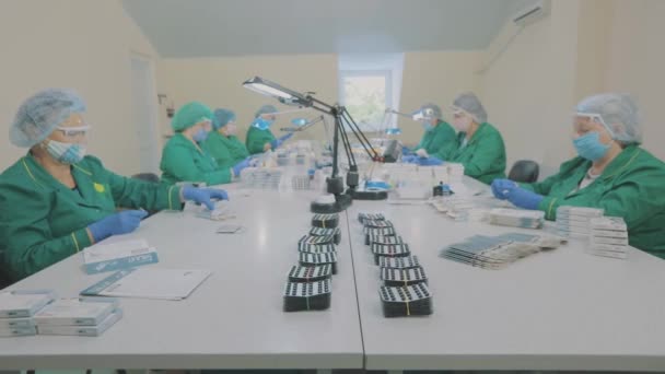 Dělníci z továrny balí prášky. Maskovaní dělníci. Workflow ve farmaceutické továrně — Stock video