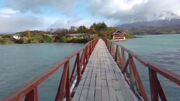 Een brug over een meer, een brug over een meer in Patagonië. Een man loopt over een brug., — Stockvideo