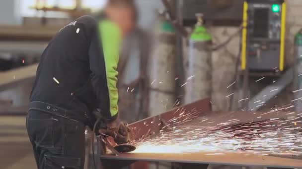 Mężczyźni wykonują prace metalowe w warsztacie, jasne iskry z narzędzia roboczego — Wideo stockowe