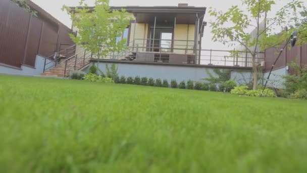 Gräsmattan närbild. Närbild av en grön gräsmatta nära huset. Ljusgrön gräsmatta på gräsmattan i huset — Stockvideo