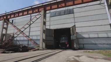 Kırmızı römorklu kırmızı bir kamyon güneşli bir günde depoya gidiyor.