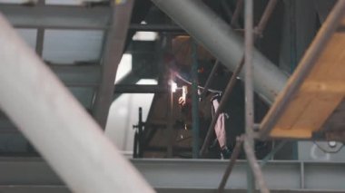 Fabrikada kaynakçı. İnşaat işçisi. Bir kaynakçı metal parçaları kaynak yapar.