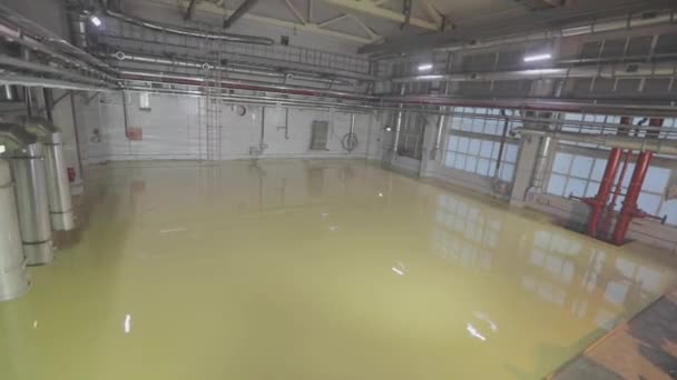 Häll självutjämnande golv. Självutjämnande golv på ett stort område, en arbetare häller självutjämnande golv i en fabriksverkstad — Stockvideo