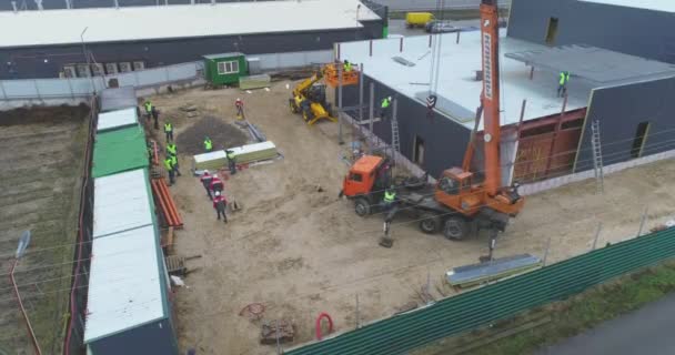 Edificio vista aérea de construcción. Excavadora en un sitio de construcción, flujo de trabajo en un sitio de construcción, la gente trabaja en un sitio de construcción — Vídeos de Stock