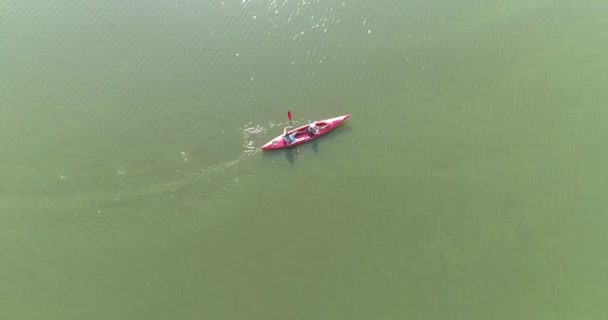 Ein Paar paddelt auf dem See. Menschen schwimmen auf dem See in einem Kanu von oben. Überfliegen Sie das Kanu im See — Stockvideo