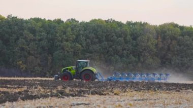Traktör sahada. Modern bir traktör tarlayı sürer. Yeşil traktör tarlayı sürüyor