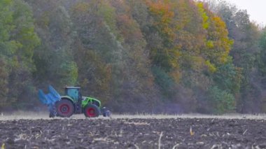 Modern bir traktör tarlayı sürer. Yeşil traktör tarlayı sürüyor. Traktör sahada..