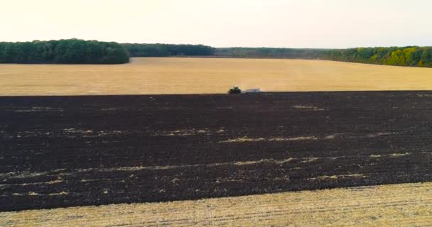 Repülj át a mezőn egy traktorral. A traktor felszántja a terepet. A traktor terepen dolgozik. Egy terepen dolgozó traktor felett repülni.. — Stock videók