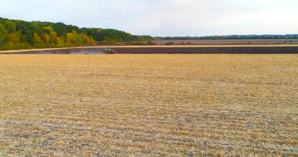 Vlieg over het veld met een tractor. Tractor ploegt het veld vanuit de lucht. De trekker werkt in het veld. Vliegen over een tractor die in het veld werkt. — Stockvideo