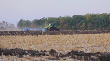 Modern bir traktör tarlayı sürer. Yeşil traktör tarlayı sürüyor. Traktör sahada..