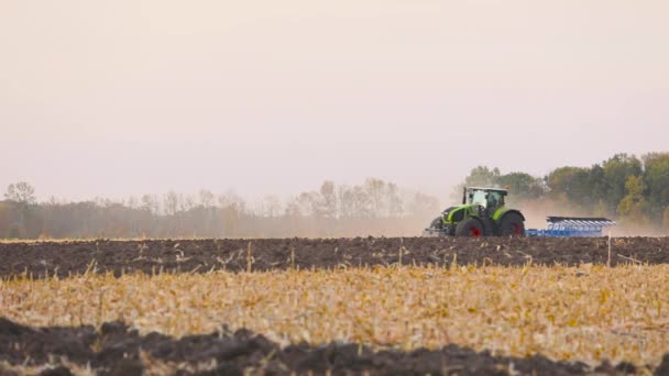 Groene trekker ploegt het veld. Tractor in het veld. Een moderne tractor ploegt het veld. — Stockvideo