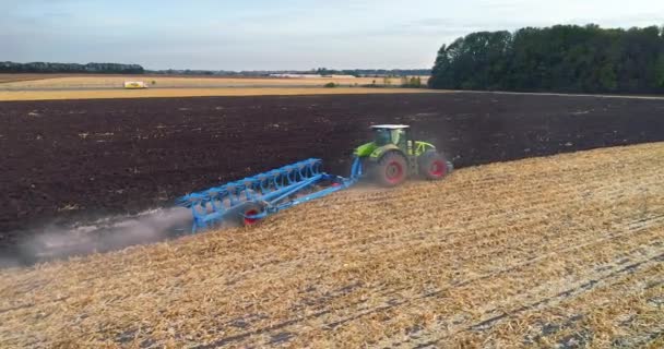 Repül a traktor felett a mezőn. A traktor felülről lefelé néz. A mező szántásának folyamata egy traktorral — Stock videók