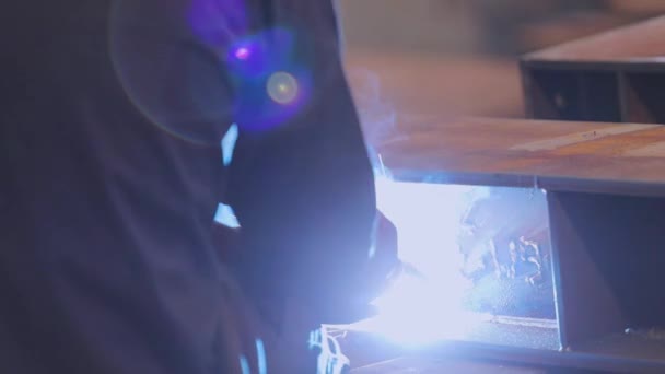 Fabrikssvetsare. En arbetare i en fabrik svetsar ihop en metallkonstruktion. — Stockvideo