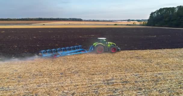 Leť přes pole s traktorem. Traktor zorává anténní zobrazení pole. Traktor pracuje v terénu. Létání přes traktor pracující v terénu. — Stock video