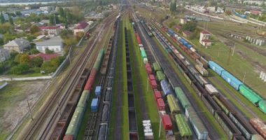 Trenler demiryolu kavşağındaki istasyona park edilmiş. Bir sürü renkli tren. Büyük sanayi demiryolu deposu.