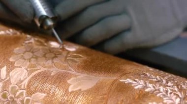 Ressam baskılar için resmi basında öğütüyor. Usta metal bir kuyuya çizim yapıyor.