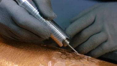 Ressam baskılar için resmi basında öğütüyor. Usta metal bir kuyuya çizim yapıyor.