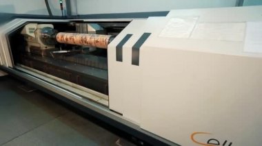 Baskı şaftı üretimi için bir makine. Adamın biri makine kuruyor. Soyut desenli basılı bir şaft. Duvar kağıdı üretimi için bir fabrika. Endüstriyel iç