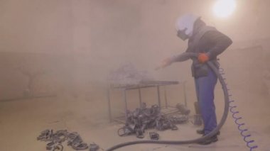 Parçayı zımparalıyorum. Fabrikada metal parçaları kumlamak. Kum püskürtme