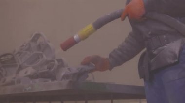 Kum temizleme. Parçayı zımparalıyorum. Fabrikada metal parçaları kumlamak..