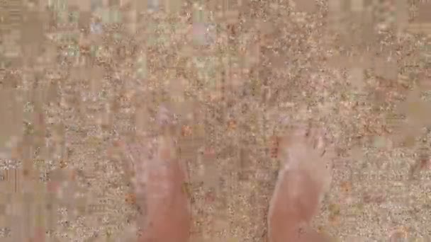 Voda omývá nohy člověka. Mužské nohy v mořských vlnách. Nohy v mořské vodě close-up — Stock video