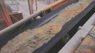 Kum ve metal toplarla taşıma bandı. Fabrikadaki taşıma bandı hattı.