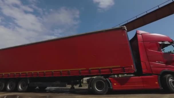 Egy piros teherautó piros lakókocsival egy raktárhoz tart egy tiszta, napos napon. — Stock videók