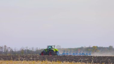 Traktör sahada. Modern bir traktör tarlayı sürer. Yeşil traktör tarlayı sürüyor