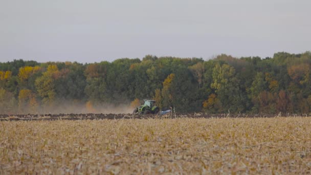 A traktor feldolgozza a mezőt. Feldolgozzuk a mezőt egy traktorral. A traktor szántja mezőgazdasági területen — Stock videók