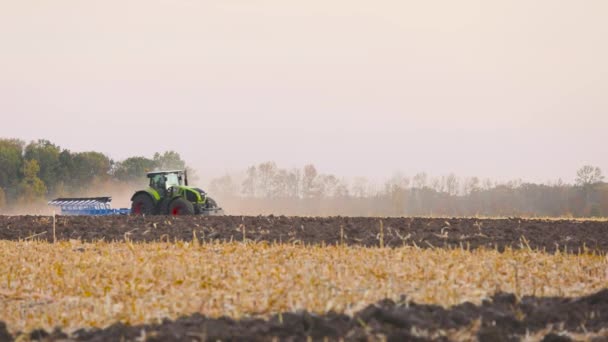 Tractor in het veld. Een moderne tractor ploegt het veld. Groene trekker ploegt het veld — Stockvideo