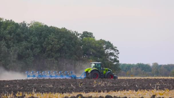 Зеленый трактор вспахивает поле. Трактор в поле. Современный трактор вспахивает поле. — стоковое видео