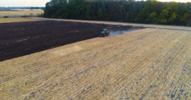 Tarlada traktörün üzerinden uçuyor. Traktör sahada tepeden tırnağa çalışıyor. Bir traktörle tarlayı sürme işlemi