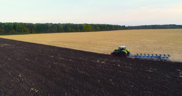 Tractor plows the field top view. The tractor works in the field. View from the drone. Modern tractor plows the field — Stock Video