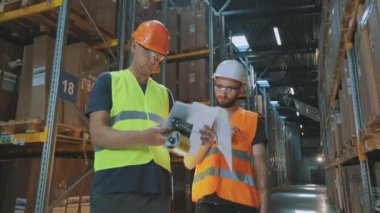 Fabrika deposunda mühendisler. Bir depoda iki işçi iş hakkında konuşuyor..
