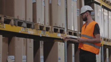 Depoda kask takan bir işçi. Depo müdürü depoyu kontrol ediyor. Modern bir depoda bir adam.