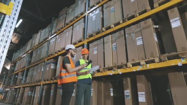 Ingenieros en un almacén de fábrica. Dos trabajadores en un almacén están discutiendo el trabajo. — Vídeos de Stock