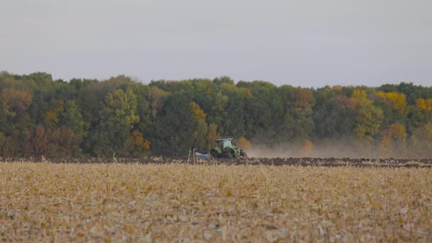 Traktor terepen. Egy modern traktor felszántja a mezőt. Zöld traktor szántja a mezőt — Stock videók