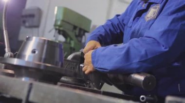 Bir adam vida ipliğini metal bir parçadan keser. Metal bir parçayla çalışıyorum. Başlatma ipliğine..