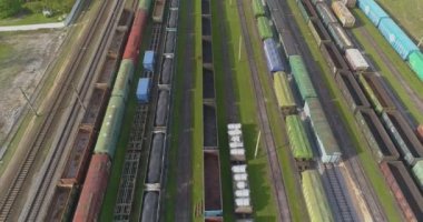 Trenler demiryolu kavşağındaki istasyona park edilmiş. Bir sürü renkli tren. Büyük sanayi demiryolu deposu.