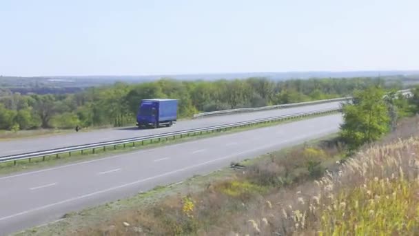 Ciężarówka jeździ po autostradzie wokół pól i drzew. Ciężarówka jedzie autostradą.. — Wideo stockowe