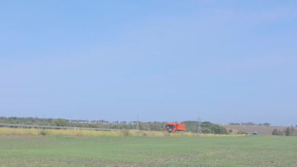 Sebuah truk sampah oranye mengemudi di sepanjang jalan. truk dump oranye naik di jalan pada hari yang cerah — Stok Video