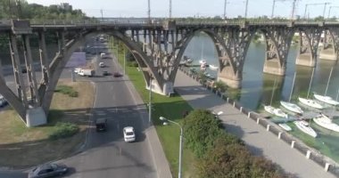 Arabalar köprünün altından geçer. Köprü manzarasının altından geçen yolda birçok araba var. Araba trafiği. Şehir manzarasında arabalar yol boyunca gider..