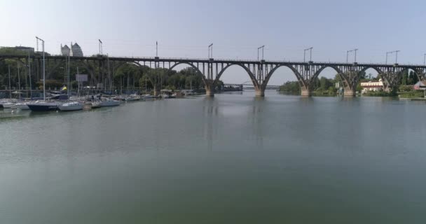 Brücke über den Fluss in einer Großstadt. In der Nähe der Eisenbahnbrücke über den Fluss in einer Großstadt. Eisenbahnbrücke über den Fluss. — Stockvideo
