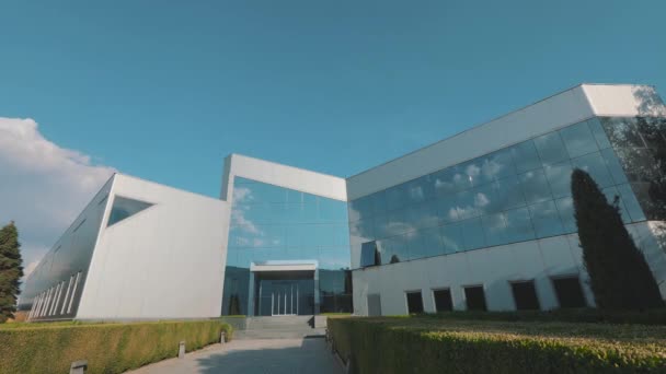 Las nubes se reflejan en las ventanas espejadas del edificio de oficinas en vueltas de tiempo — Vídeo de stock