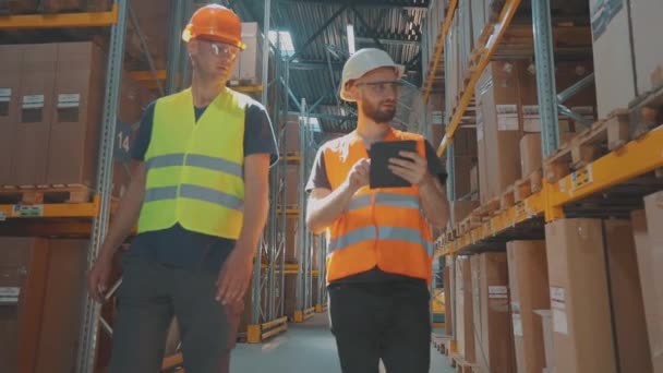Två arbetare kommer att gå till det moderna lagret. arbetsprocessen i lagret. Modern fabrik, industriell interiör — Stockvideo