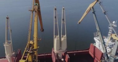 İskele vinçleri kuru bir kargo gemisini yüklüyor. Büyük port vinçlerinin işi