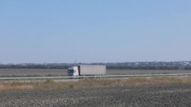 Kamyon şehrin dışında düz ve modern bir yolda gidiyor. Kamyon güneşli bir günde yol boyunca gidiyor.