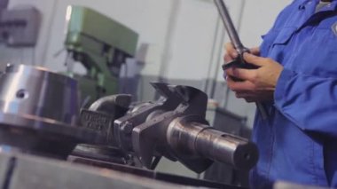 Başlatma ipliğine. Bir adam vida ipliğini metal bir parçadan keser. Metal bir parçayla çalışmak